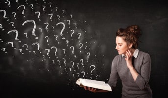 Confused woman reading a book with question marks coming out from it